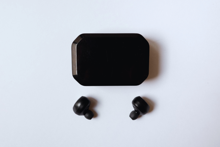 Black wireless earbuds and their rectangular charging case on a white background.