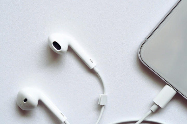White earbuds and a smartphone lie on a white surface