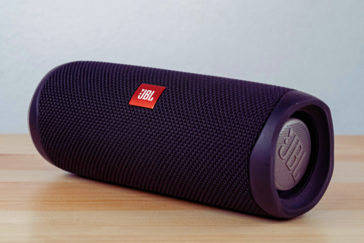 A black JBL portable Bluetooth speaker on a wooden surface. 